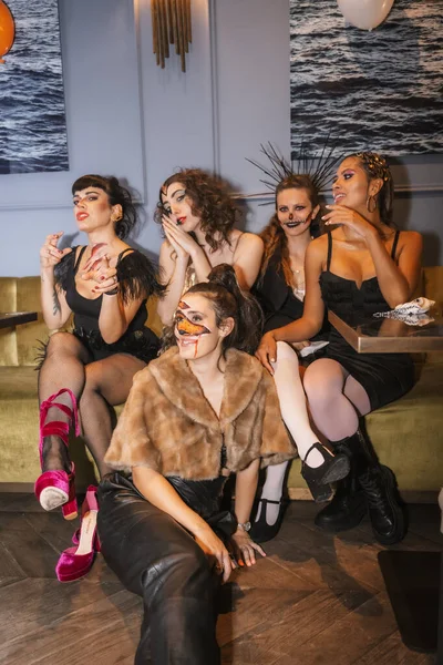 ディスコのナイトクラブで友達とハロウィーンパーティー メイクでソファに座っている女性の友人のグループの肖像画 — ストック写真
