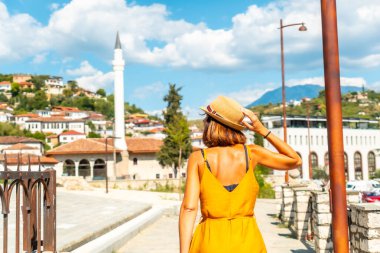 Arnavutluk 'un Berat kentinde yaz tatilinde binlerce pencereli bir şehirde yürüyen genç bir kadın