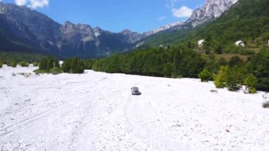 Kuru nehir kıyısındaki 4x4 'lük bir araba, yazın kurak nehir kıyısındaki Rragam' a doğru Valbona Vadisi, Theth Ulusal Parkı, Arnavutluk Alpleri ve Arnavutluk üzerinden gidiyor.