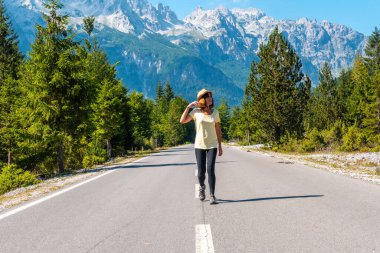 Valbona vadisinde ağaçların, Theth ulusal parkının, Arnavut Alpleri ve Valbona Arnavutluk 'un yanındaki yolda yürüyen bir turist