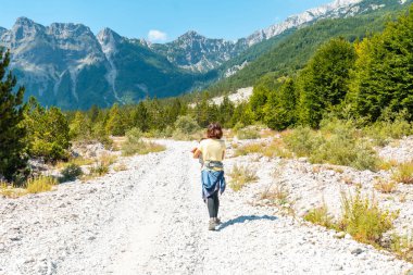 Oğluyla birlikte Valbona Vadisi 'nde ağaçlar, Theth Ulusal Parkı, Arnavut Alpleri ve Arnavutluk' un yanında yürüyen bir yürüyüşçü.