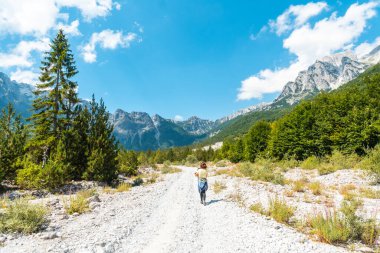 Oğluyla birlikte Valbona Vadisi 'nde ağaçlar, Theth Ulusal Parkı, Arnavut Alpleri ve Arnavutluk' un yanında yürüyen bir yürüyüşçü.