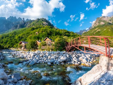 Valbona Vadisi nehri boyunca uzanan kırmızı köprü ve bazı ahşap evler veya kulübeler, Theth Ulusal Parkı, Arnavut Alpleri, Arnavutluk