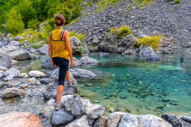 Arnavutluk 'un Theth ulusal parkı vadisindeki turkuaz su deposunda genç bir kadın. Alp Dağları