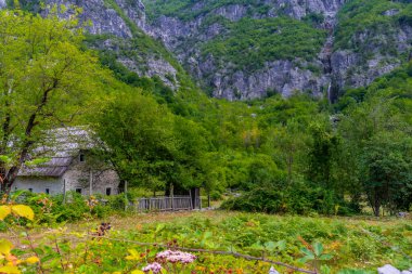 Arnavutluk 'un Theth Ulusal Parkı' ndaki Grunas şelalesinin altında ahşap bir kulübe. Arnavut Alpleri