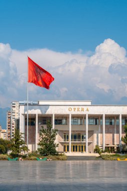 Tiran 'daki Skanderbeg Meydanı' ndaki Kültür veya Opera Sarayı ve Arnavutluk bayrağı rüzgârda savruluyor