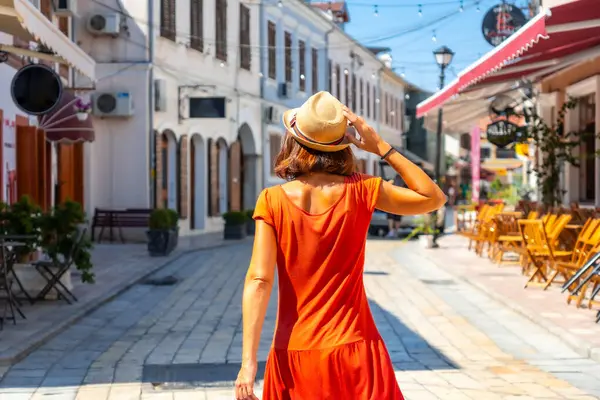 Kırmızı elbiseli turist kadın Shkoder şehrinin sokaklarında tatilin tadını çıkarıyor. Arnavutluk