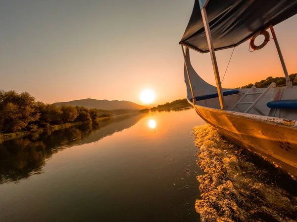 Orange sunset sailing across the lake in a traditional boat on a sightseeing excursion from Shkoder in Shiroka. Albania