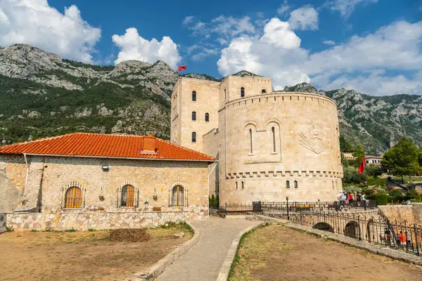 Kruje Kalesi 'ni ve kalesini ziyaret eden turistler, arka planda dağlar ve duvarlar var. Arnavutluk