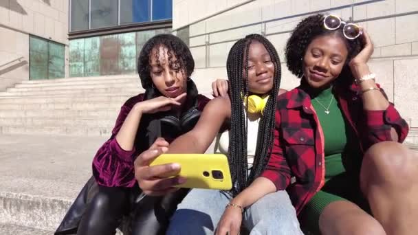 屋外でモバイルを共有しながら笑顔の3人の多民族友人の低い角度ビュー — ストック動画