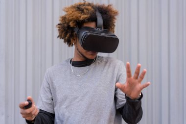 Sanal gerçeklik gözlüğü kullanan oyuncu bir adamın kentsel gri arkaplanlı yatay fotoğrafı