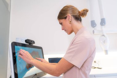 Modern teknolojiyi kullanan dişçi tarama sonuçlarını bir klinikte analiz ediyor.