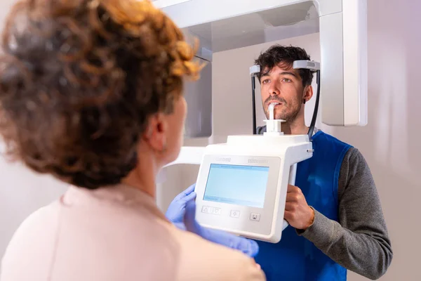 Man standing in front of a x-ray machine in a dental clinic