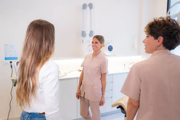 Two members of dental clinic staff and a customer talking in a room