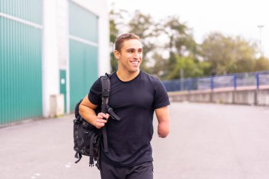 Happy and young athlete with one arm amputated arriving at the gym clipart