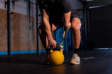 Tanınmayan engelli bir adamın üzerinde yapay ışık bulunan koyu renkli bir portre. Kettlebell kullanıyor.