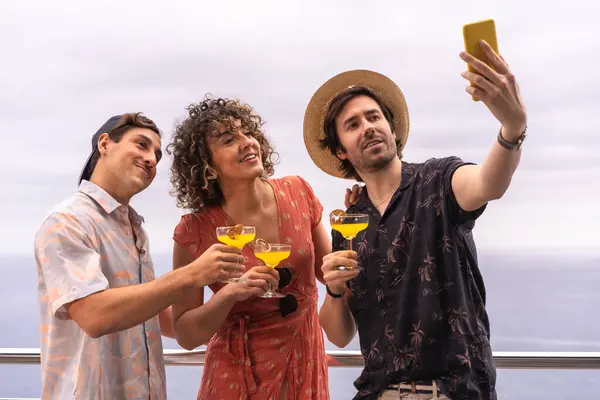 Colleagues toasting while taking a selfie in a terrace with sea views