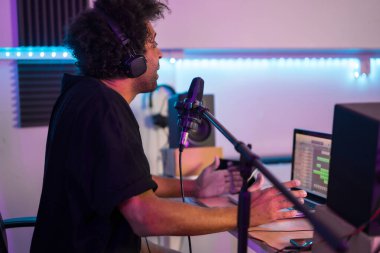 Bir stüdyodan podcast kaydeden bir müzisyenin yan görüntüsü