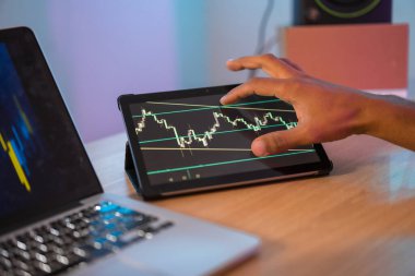Tanınmayan bir iş adamının dijital tabletteki borsa verilerini kontrol ederken çekilmiş fotoğrafı.