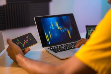 Bilgisayarda ve tablette kriptoyla yapılan yatırım verilerini analiz eden adam