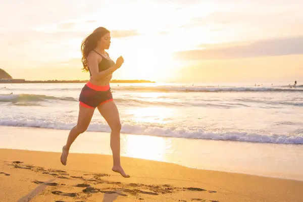 Beauty woman running along a sandy beach during sunset