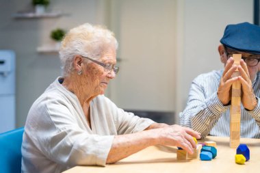 Old woman and man in a nursing home playing skill games clipart