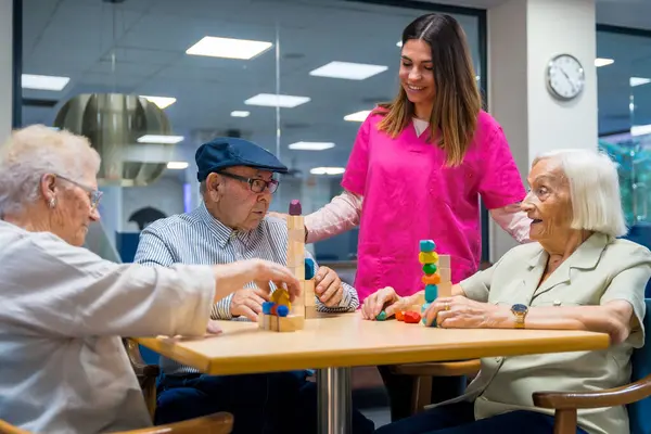 Elder people playing skill games next to a nurse in a nursing home