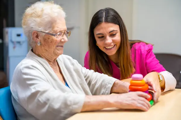Aranyos Nővér Segít Egy Nőnek Társasozni Ügyességi Játék Egy Idősek — Stock Fotó