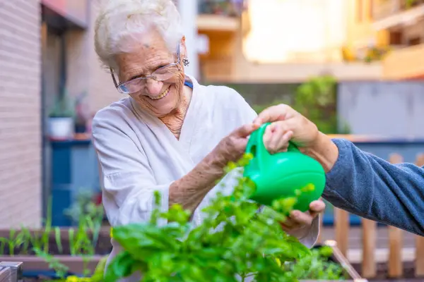 Senior woman watering plants in the backyard of a nursing home