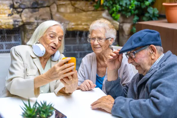 Three elder people using phone and listening to music in a geriatric