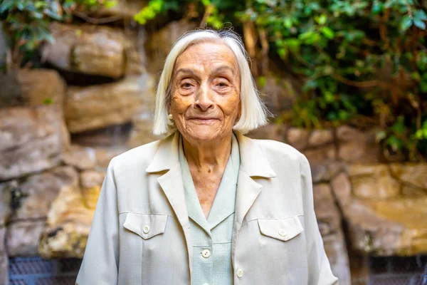 Smiling elder woman looking at camera in the garden of a nursing home