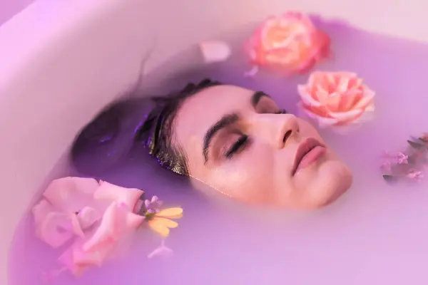 Artistic portrait from above of a calm woman in a bath milk with flowers