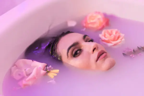 Artistic portrait from above of a sensual woman in a bath milk with flowers