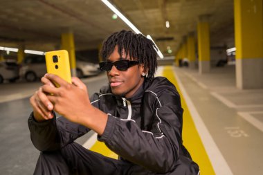 Garajda oturan Afrikalı havalı bir adamın yakın plan portresi.