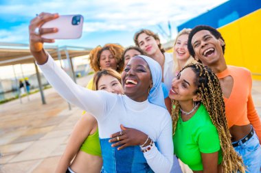 Mutlu Müslüman Afrikalı kadın arkadaşlarıyla gülerken selfie çekiyor.