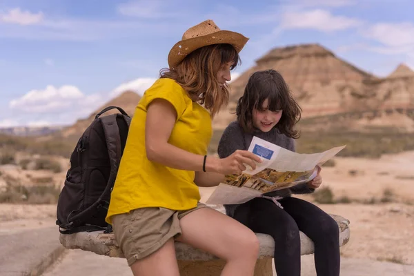 Happy and curious sisters reading information sitting on a national park