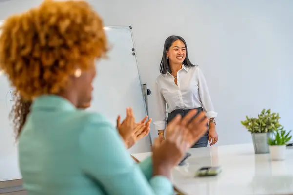 Chinese woman proud while people applauding her presentation in a coworking