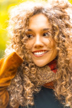 Sonbaharda parka bakan kıvırcık saçlı, şehvetli bir kadının dikey portresi.