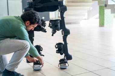 Mekanik dış iskelet mühendisi müşteriye teslim edilmeden önce robotu kontrol ediyor. Modern bir hastanede fizik tedavi, robot iskeleti. Fizyoterapi Bilimadamları, Mühendisler ve Doktorlar