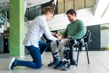 Mekanik dış iskelet, fizyoterapist engelli insanın dizlerine bant yerleştirerek robotik iskeletini, fizyoterapisini modern bir hastaneye yerleştiriyor.: