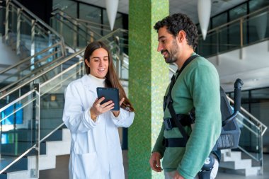 Mekanik dış iskelet, kadın fizyoterapist tablet ile konuşan engelli insan robotik iskelet, modern bir hastanede fizyoterapi, gelecekteki fizyoterapi