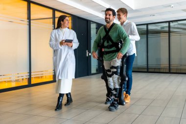 Mekanik dış iskelet, cihazlı kadın doktor rehabilitasyonda robotik iskeleti olan engelli biriyle yürüyen, modern hastanede fizyoterapi, gelecekteki fizyoterapi