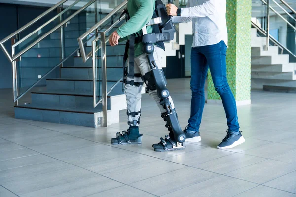 Mekanik dış iskelet, fizyoterapist tanınmayan engelli biriyle modern bir hastanede robot iskeleti ve fizyoterapisi ile yürüyor.: