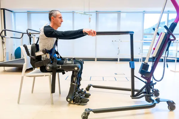 Mechanical exoskeleton. Disabled person with robotic skeleton in rehabilitation trying to get up alone, Physiotherapy in a modern hospital
