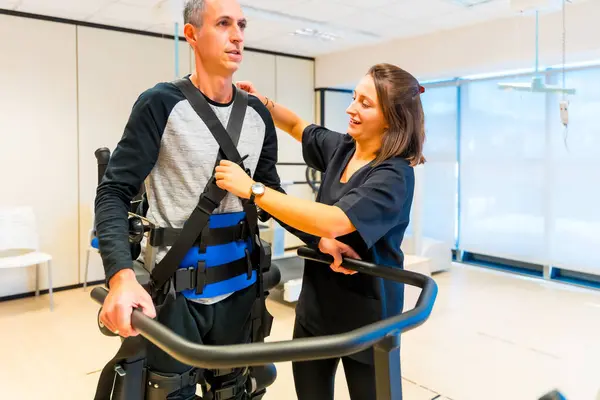 Mechanical exoskeleton. Female physiotherapy medical assistant with disabled person lifted with robotic skeleton. Futuristic rehabilitation, Physiotherapy in a modern hospital