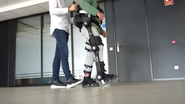 Mechaniczny Egzoszkielet Fizjoterapeuta Spacerujący Nierozpoznawalną Osobą Niepełnosprawną Robotycznym Szkieletem Fizjoterapia — Wideo stockowe