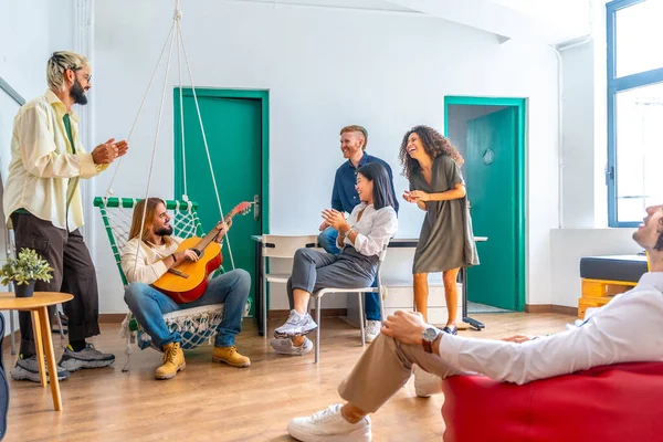 Distracted people playing guitar and singing during a break in a coworking