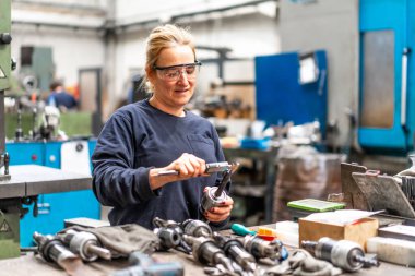 Sayısal kontrol sektöründe çalışan kadın fabrika işçisi matkap uçlarını, endüstriyel fabrikayı ölçüyor.