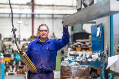 Sayısal kontrol sektöründeki fabrika işçisi bir müşteriye yükseltilmiş metal parçasını teslim ediyor, endüstriyel fabrika