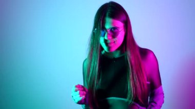 Uzun saçlı, güneş gözlüklü, neon ışıklarla dans eden şehvetli bir transseksüel.